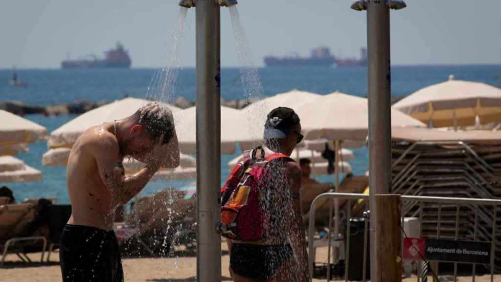 Varias personas se mojan en las duchas de la playa de la Barceloneta / EUROPA PRESS