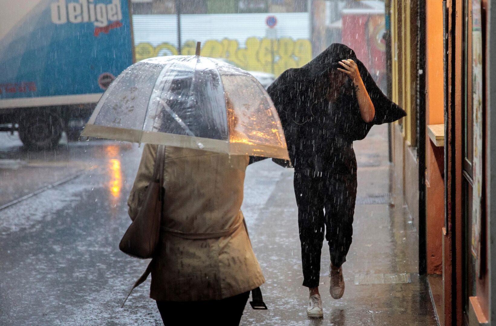 Dos personas se resguardan del temporal de lluvia / EFE