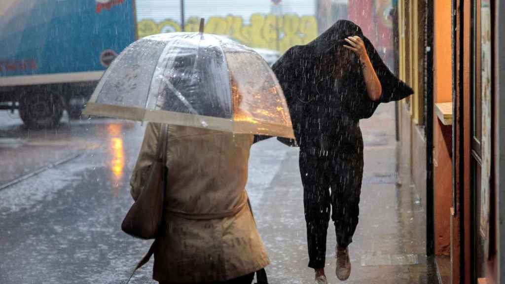 Dos personas se resguardan de un temporal de lluvia