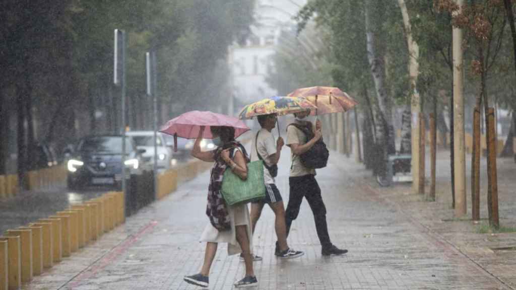 Tres personas se cubren de la lluvia con paraguas