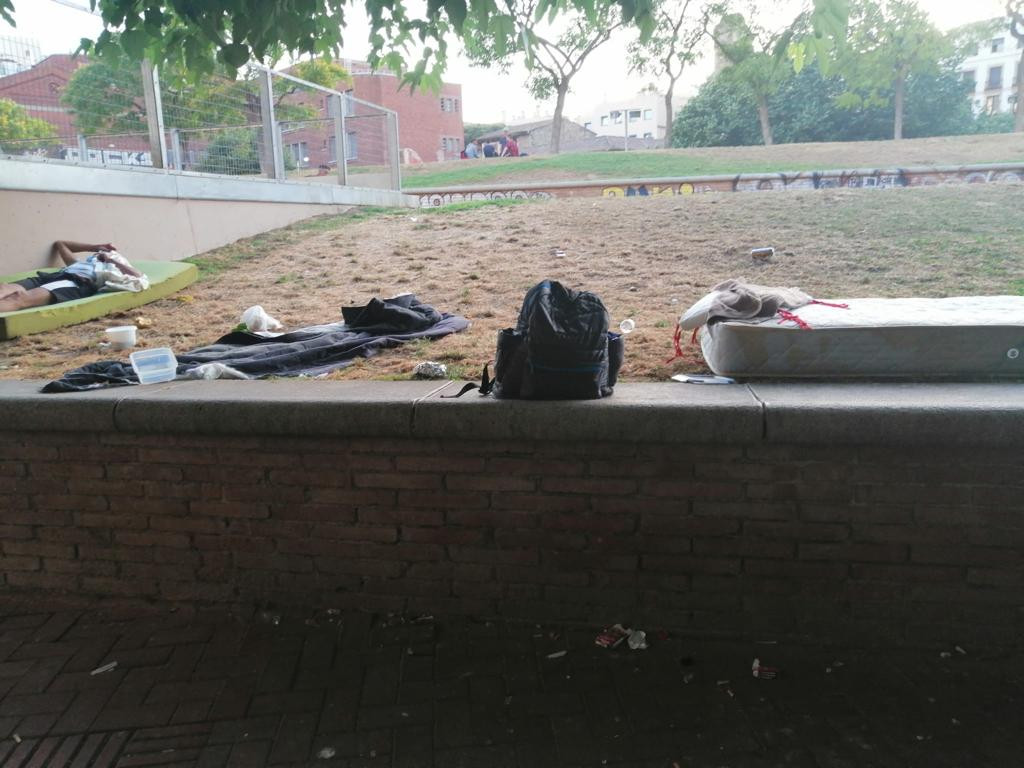 Un hombre duerme sobre el colchón en el parque de Sant Pau del Camp rodeado de basura / CEDIDA