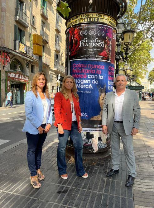 Marilén Barceló, Eva Parera y Òscar Benítez junto al cartel de la Mercè que han colgado / VALENTS