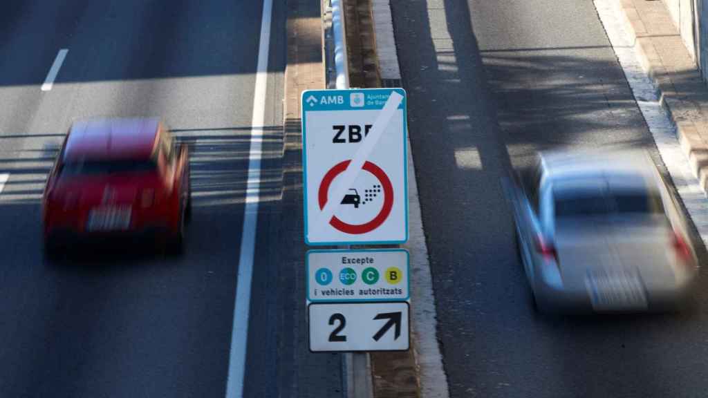 Dos vehículos circulan junto a un cartel de la Zona de Bajas Emisiones / EFE