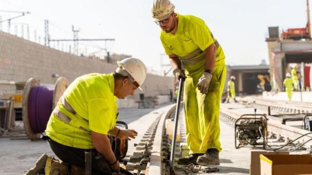 Dos obreros trabajan sobre una de las vías de Rodalies de Barcelona