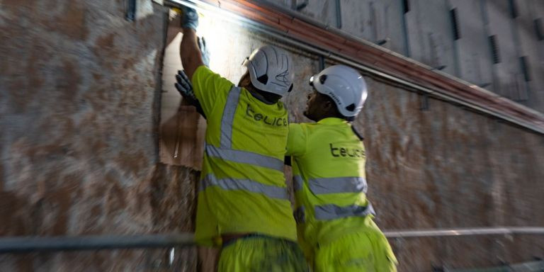 Dos operarios trabajan con un cuadro eléctrico dentro del túnel de Renfe en Sant Andreu / LUIS MIGUEL AÑÓN - METRÓPOLI