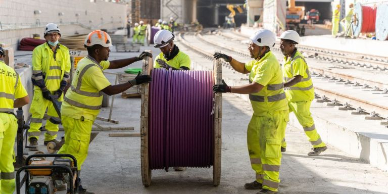 Varios trabajadores transportan una bobina de cableado eléctrico / LUIS MIGUEL AÑÓN - METRÓPOLI