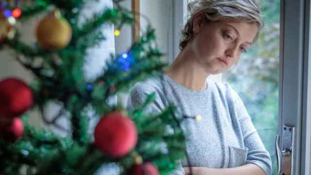 Una mujer pensativa junto a un árbol de Navidad / QUIRÓNSALUD