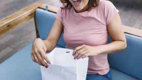 Mujer abriendo una bolsa de papel / FREEPIK