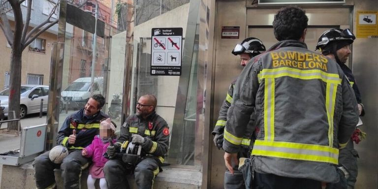 La niña con los bomberos después de ser rescatada junto a su abuelo / TWITTER ESCOLA DEL MAR