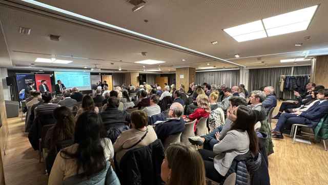 Asistentes a un foro de inversores, con los tres ponentes al fondo, en Barcelona / MA