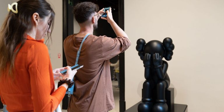 Un chico fotografía una figura de Kaws en el Moco Museum / LUIS MIGUEL AÑÓN - METRÓPOLI