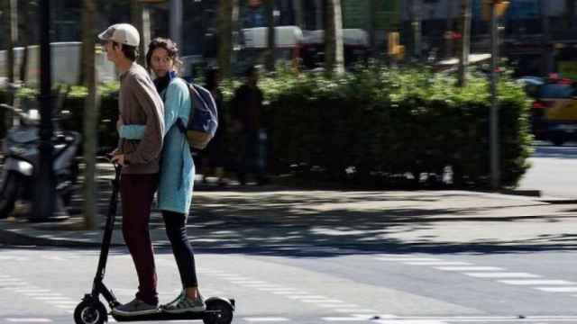 Dos personas circulan en un patinete en Barcelona