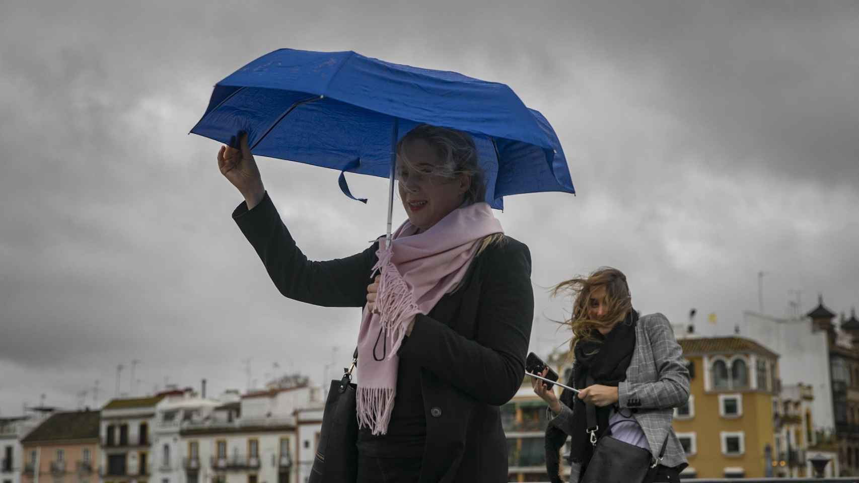 Dos mujeres intentan protegerse del viento con su paragüas
