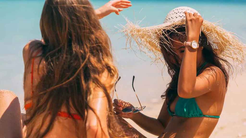 Dos jóvenes se protegen del sol en la playa / PEXELS