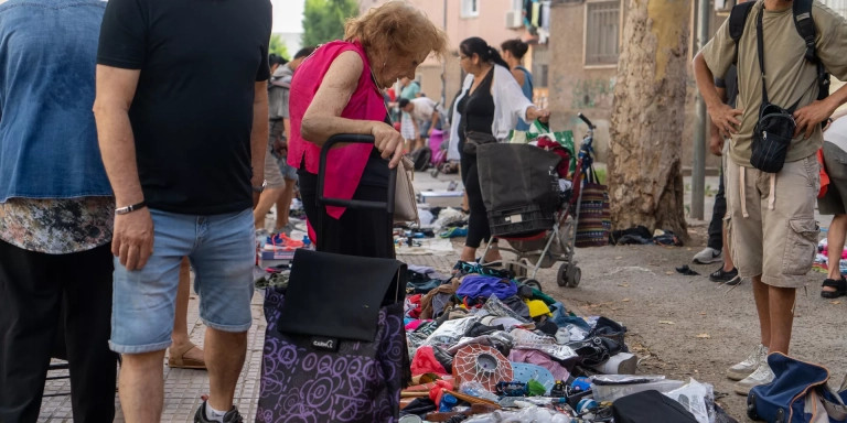 Una mujer contempla la mercancía expuesta en el mercadillo de la miseria de Badalona / GALA ESPÍN