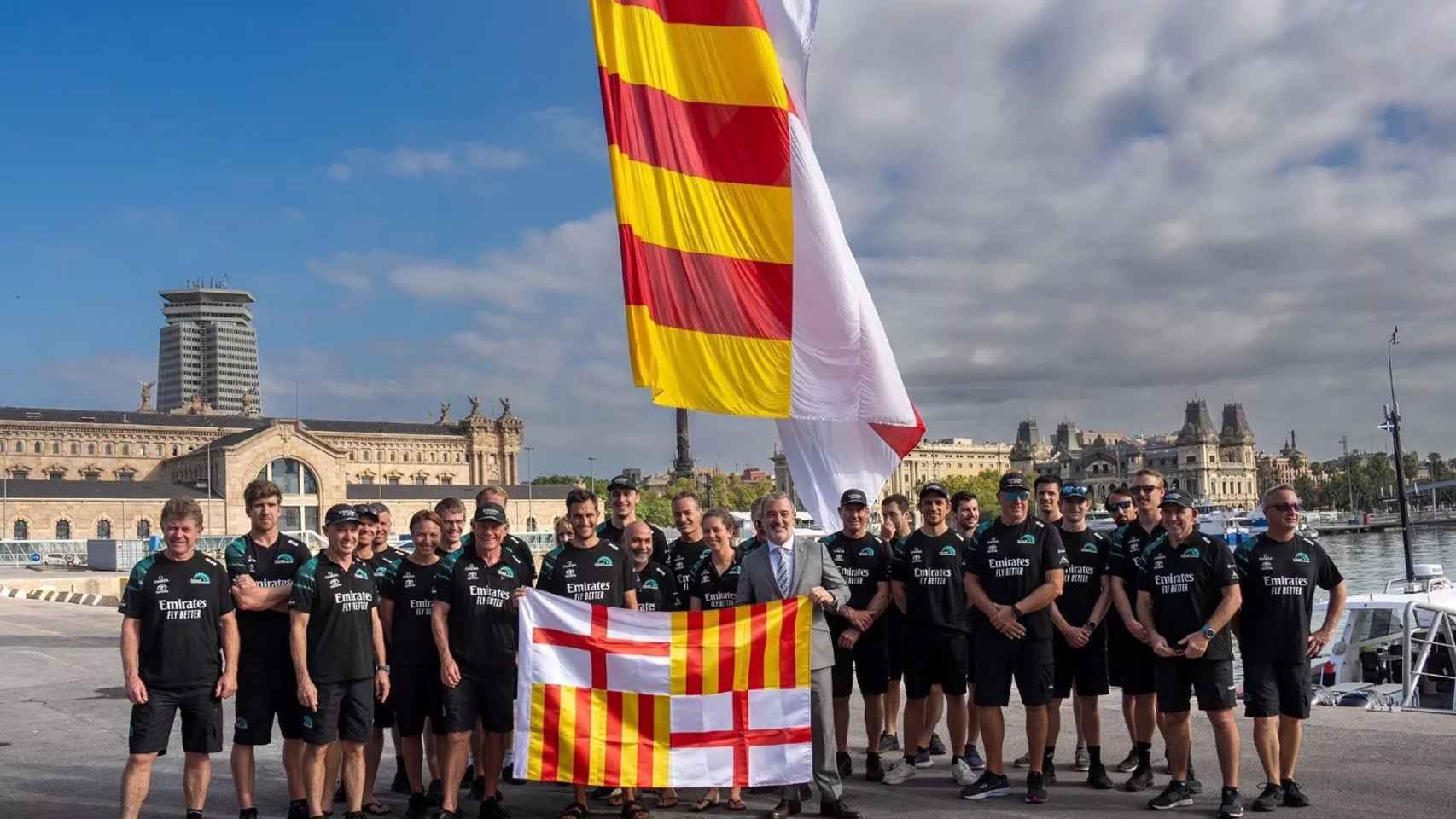 Collboni entrega la bandera de Barcelona al equipo Emirates Team New Zeland de la Copa América. / AYUNTAMIENTO DE BARCELONA