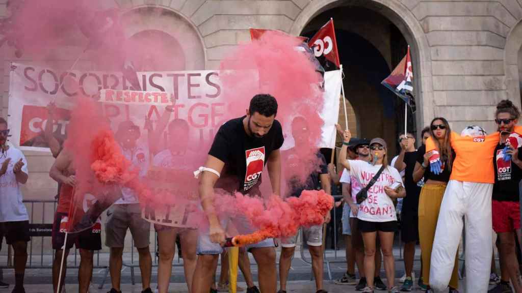 Una persona con una bomba de humo durante una concentración de CGT-Socorristas, en la plaza Sant Jaume /