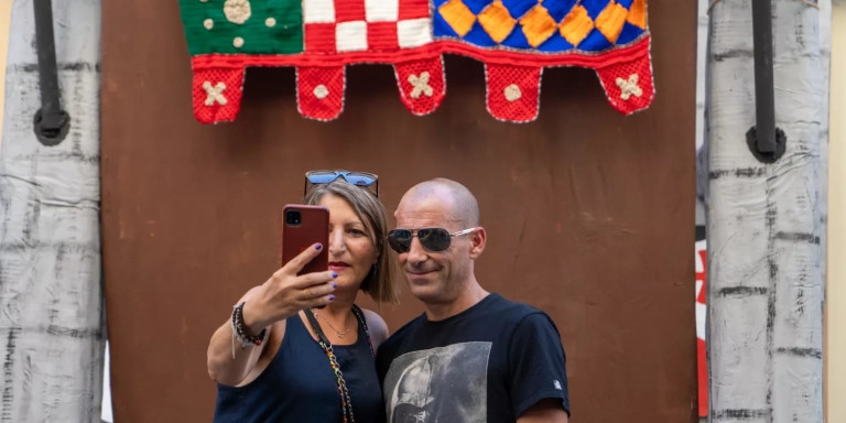 Dos visitantes se hacen una foto en una calle decorada para las fiestas de Sants / GALA ESPÍN