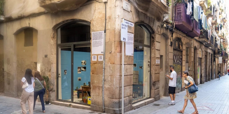 Vecinos curiosos se acercan a ver a la artista Andrea Roma en el Raval / SIMÓN SÁNCHEZ