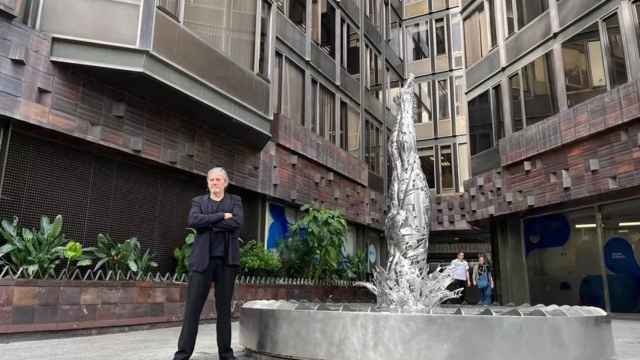 EL artista Jordi Díez posa junto a su obra 'El Saltador', en la entrada de la Torre Urquinaona. - EUROPA PRESS