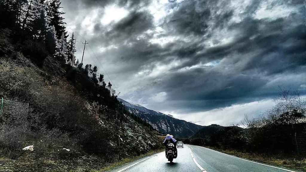 Motoristas en ruta con cielo nublado