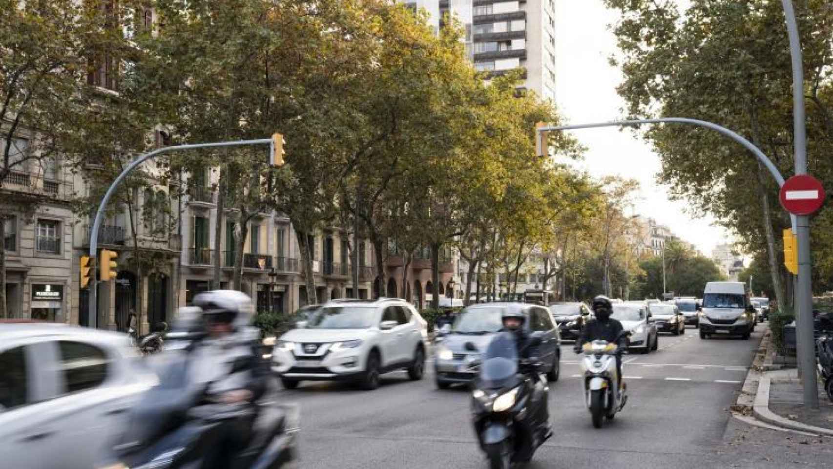 Coches y motos circulan por una calle de Barcelona con tráfico