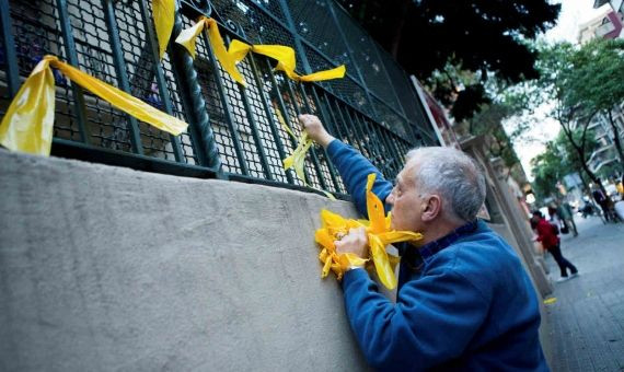 Un homnre retitando lazos amarillos / EFE