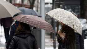 Varias personas pasean por Barcelona con paraguas a causa de la lluvia