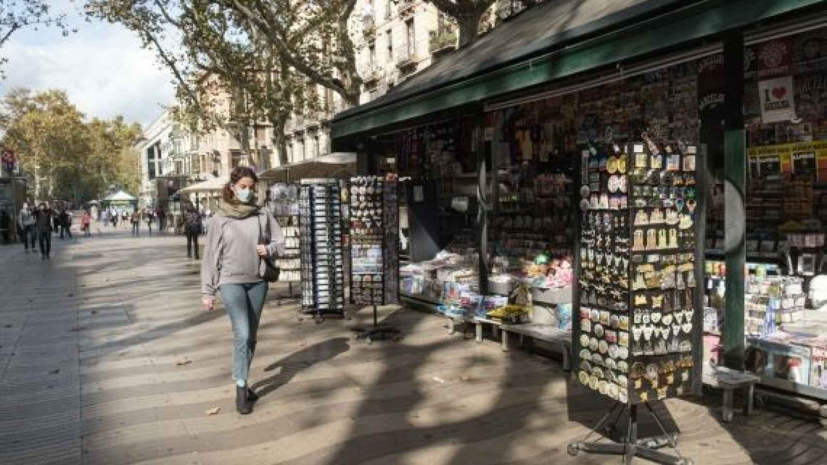 Una mujer camina delante de un kiosko en La Rambla de Barcelona