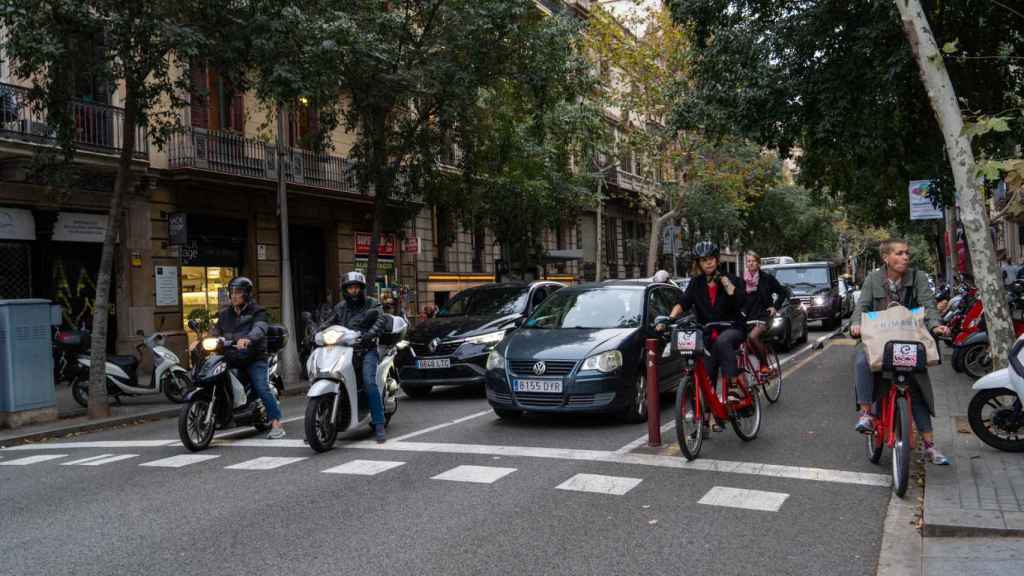 Coches, motos y bicicletas circulando por la calle València, en el Eixample barcelonés