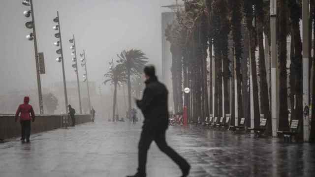 Un hombre camina bajo la lluvia por el paseo marítimo de Barcelona