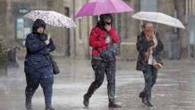Tres personas cubiertas con paraguas durante una jornada de lluvias en Barcelona