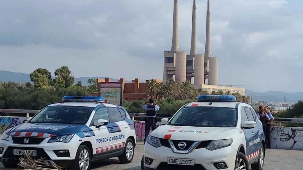 Dos coches de mossos con las chimeneas de Sant Adrià de fondo