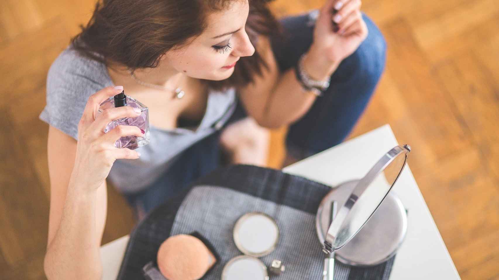 Una mujer se perfuma frente al espejo