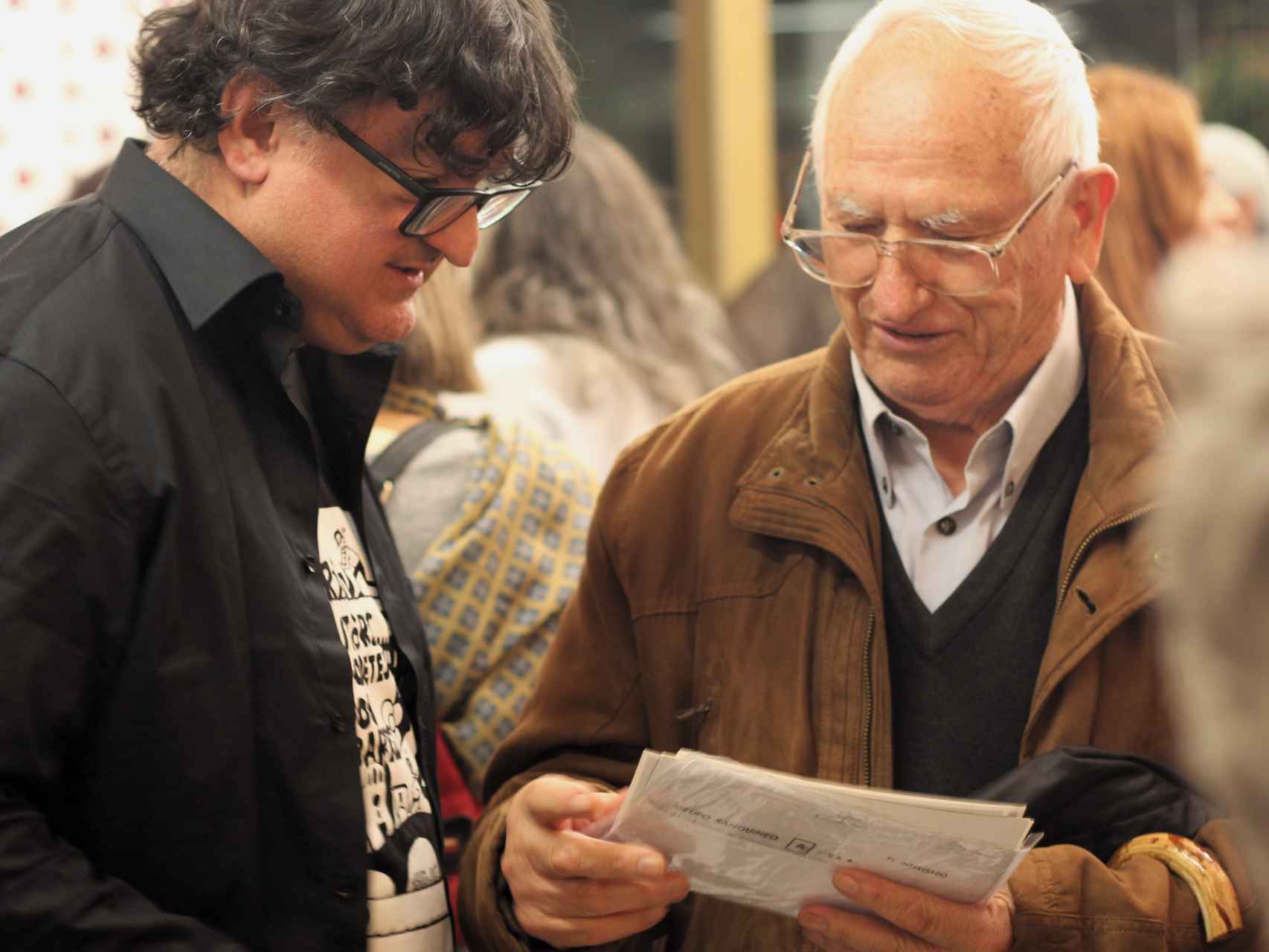 El presidente del Arxiu, Jordi Sánchez, ojea unas fotos con Vicente Martí, antiguo empleado del Instituto Mental de la Santa Creu, durante el aniversario de la entidad