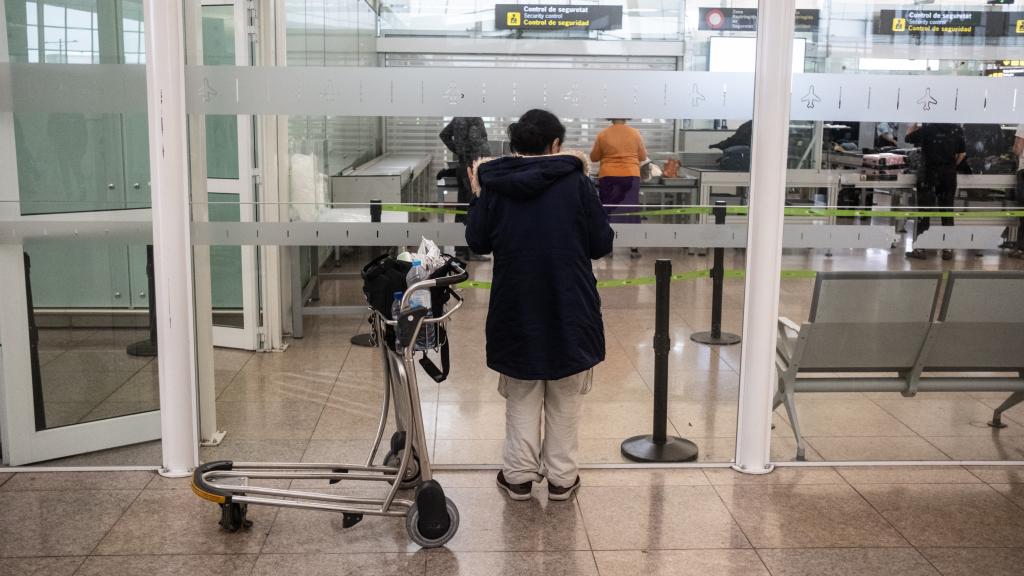 Una mujer espera en el control de seguridad del Aeropuerto de Barcelona-El Prat