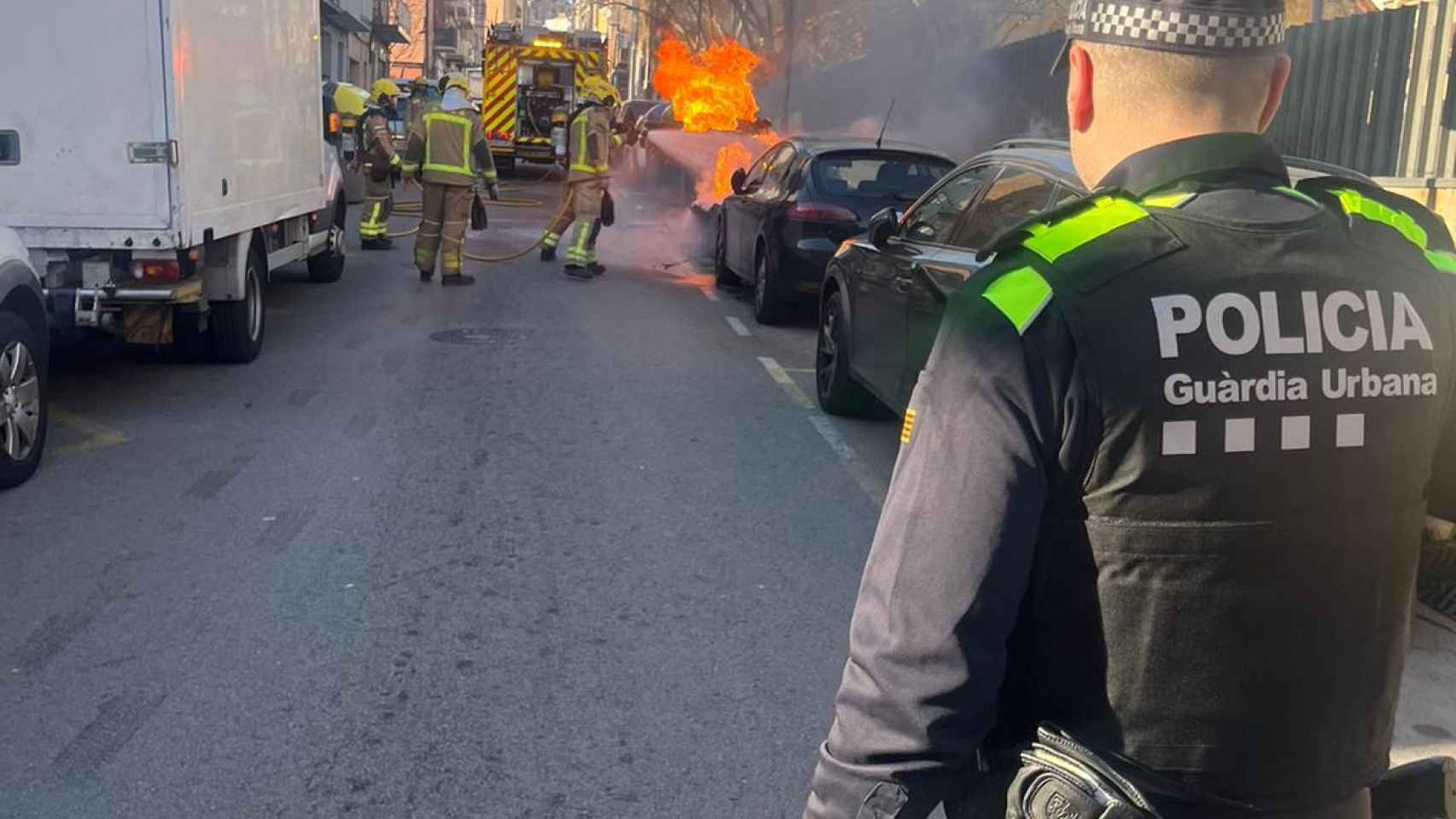 Un agente de la Guardia Urbana ante el incendio de contenedores en La Salut