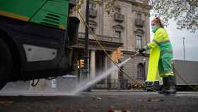 Una trabajadora riega una calle con una manguera en enero en Barcelona