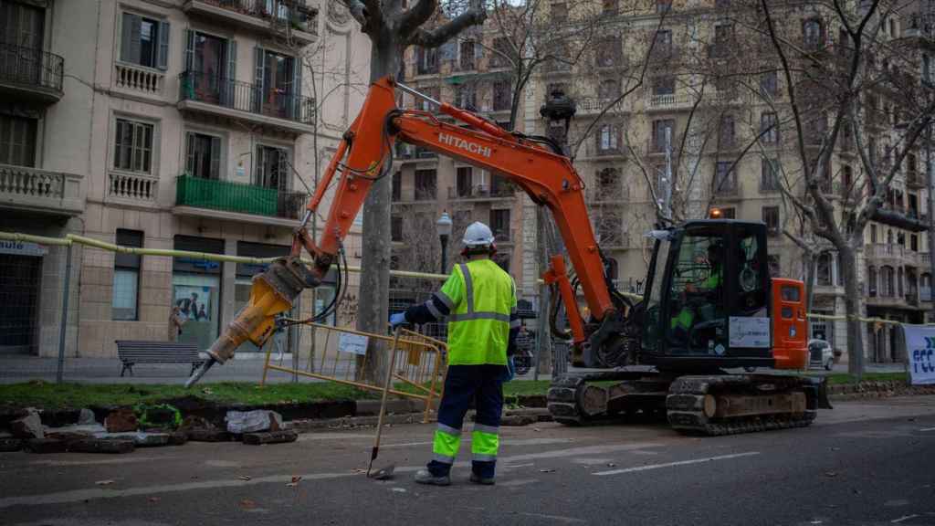 Un obrero y una máquina excavadora trabajan en las obras para unir el tranvía por la Diagonal