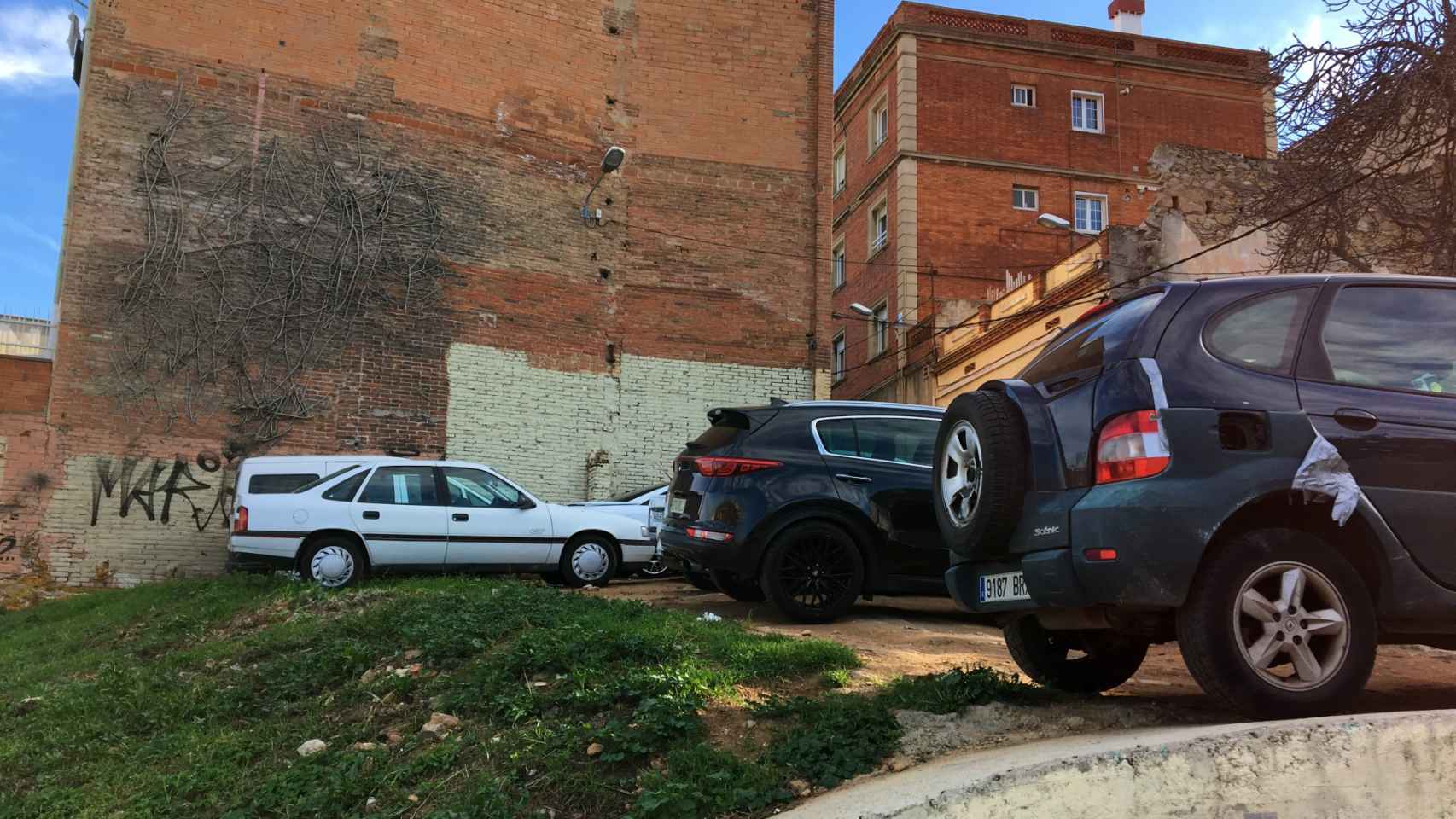 Vehículos aparcados junto a un edificio degradado en la Font de la Guatlla