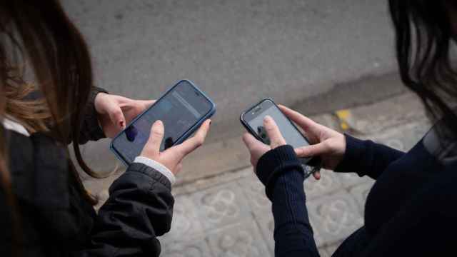 Dos jóvenes interactúan con sus teléfonos móviles