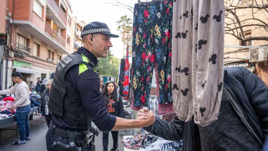 Uno de los agentes de la Policía Local de Santa Coloma hablando con un paradista del mercadillo de Fondo