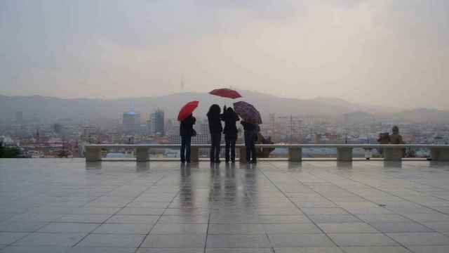 Varias personas se resguardan de la lluvia bajo unos paraguas en Barcelona