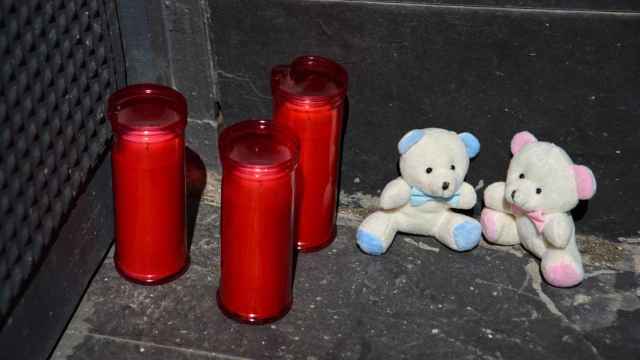 Tres velas y dos osos de peluche en la puerta del garaje de la vivienda donde un hombre ha matado presuntamente a su mujer y sus dos hijos menores