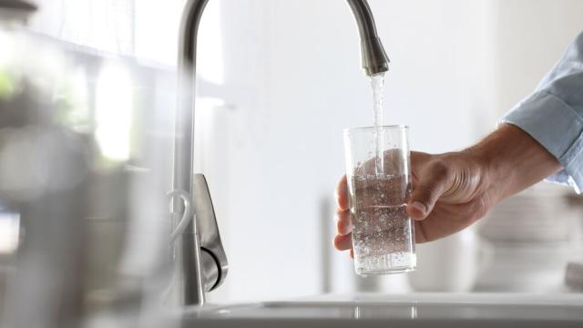 Una persona llenando un vaso de agua del grifo