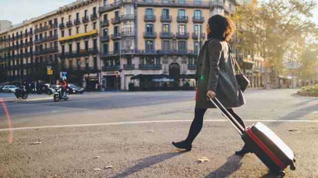 Una mujer pasea con una maleta en Barcelona