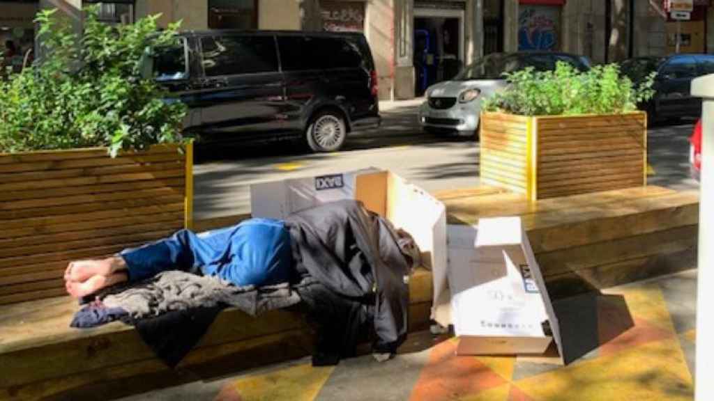 Un hombre sin hogar durmiendo en la superilla de Sant Antoni