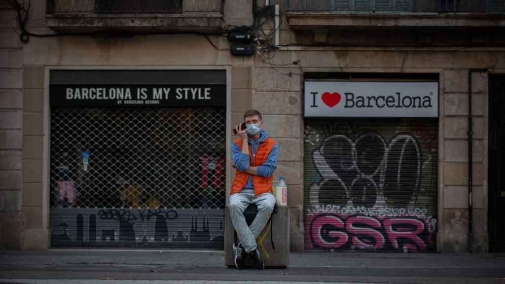 Un hombre escucha a su teléfono móvil frente a dos tiendas turísticas en Barcelona