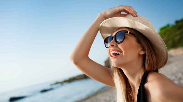 Una joven se protege del sol con sombrero y gafas