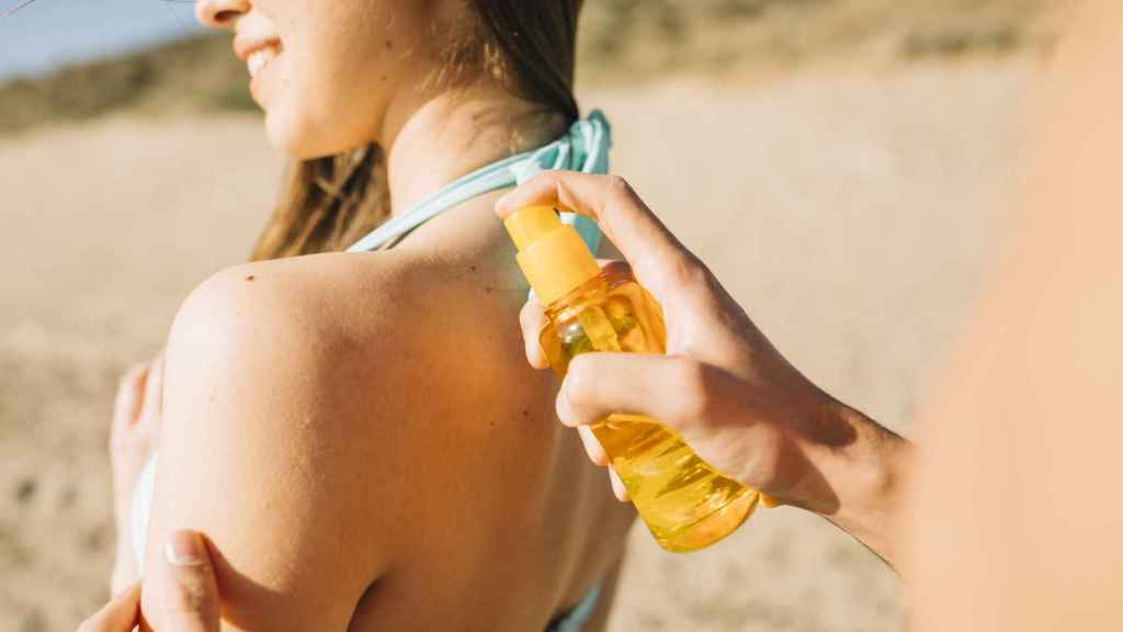Un chico extiende crema solar en los hombros de una joven